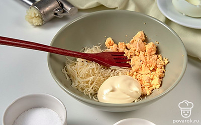 Сделайте начинку. Соедините желтки, сыр и чеснок. Заправьте майонезом и хорошо перемешайте. Посолите и поперчите по вкусу.