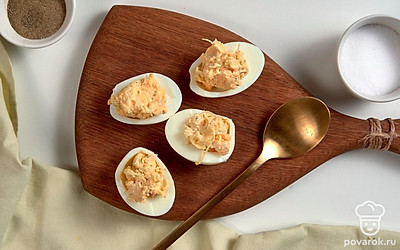 Нафаршируйте яйца. Возьмите чайную ложку и наполните белки начинкой. Сверху аккуратно сделайте "шапочку".