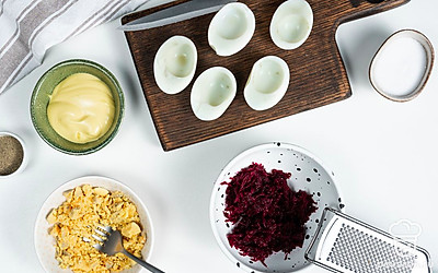 Подготовьте ингредиенты. Яйца разрежьте пополам, уберите желтки, измельчите их в крошку. Мелко натрите свеклу.