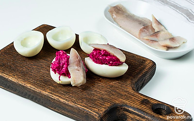 Приготовьте блюдо. Соедините желтки со свеклой, приправьте солью и перцем, заправьте майонезом и активно перемешайте. Нафаршируйте яйца и положите сверху по кусочку селедки.