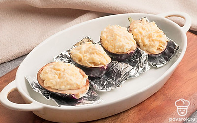 Баклажаны разрежьте пополам, выньте столовой ложкой середину и нафаршируйте полученной начинкой. Застелите форму для запекания фольгой. Выложите в нее баклажаны и запекайте их в разогретой до 180 градусов духовке в течение 15-20 минут.