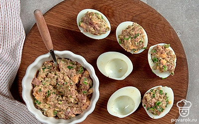 Нафаршируйте яйца. Желтки соедините с печенью трески, зеленым луком и маринованными огурцами. Сдобрите майонезом, тщательно перемешайте. Распределите начинку в половинки яиц.