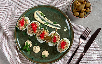 При подаче украсьте фаршированные яйца красной икрой.