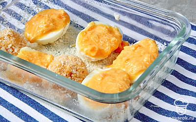 Подготовьте блюдо к запеканию. Жаропрочную форму смажьте сливочным маслом, присыпьте сухарями. В половинки белков распределите желтково-сырную начинку, выложите в форму. Из оставшегося фарша сформируйте небольшие шарики, запанируйте их в муке, обжарьте до румяности на оставшемся сливочном масле и выложите между яичными половинками.