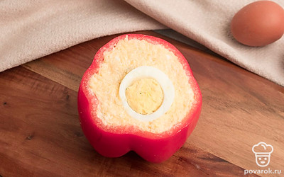 Очистите яйца от скорлупы. Нафаршируйте болгарский перец сырно-майонезной смесью, положив в центр куриное яйцо.