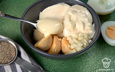 Приготовьте начинку. Яйца разрежьте пополам, извлеките желтки и разомните их вилкой. Чеснок мелко нарежьте. В одну выложите желтки, плавленый сыр, чеснок, майонез, соль и перец. Тщательно перемешайте до однородной массы.