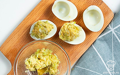 Нафаршируйте яйца. В отдельной тарелке разомните желтки в мелкую крошку. Добавьте огурцы и майонез. Посолите, поперчите. Перемешайте. Ложечкой аккуратно разложите начинку по яичным белкам. Сверху посыпьте хрустящим луковым топпингом.