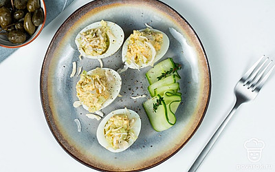 На блюдо выложите листья салата. Сверху разместите яйца, фаршированные желтком и луком. Немного охладите и подавайте к столу.