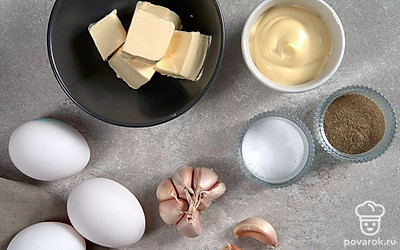 Яйца сварите вкрутую, остудите, почистите. Разрежьте вдоль пополам, извлеките желток. Сливочное масло заранее достаньте из холодильника, оно должно быть комнатной температуры. Чеснок очистите от шелухи. Овощи и зелень для подачи вымойте, обсушите бумажными полотенцами, зелень измельчите, огурец нарежьте тонкими слайсами.