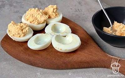 Сформируйте закуску. Яичные желтки соедините с чесноком, сливочным маслом, майонезом. Приправьте солью и молотым перцем, интенсивно перемешайте. Приготовленной салатной смесью наполните каждую половинку белка.