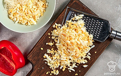 Приготовьте начинку для перцев. Сыр смешайте с тертыми вареными яйцами. Добавьте измельченные укроп и чеснок. Заправьте майонезом, посолите и поперчите по вкусу.