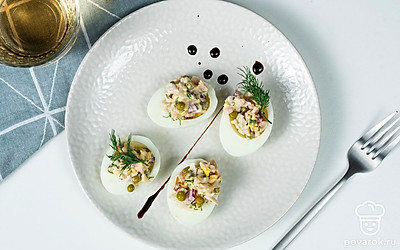 Яйца, фаршированные кальмарами, украсьте петрушкой. Подавайте закуску в охлажденном виде.