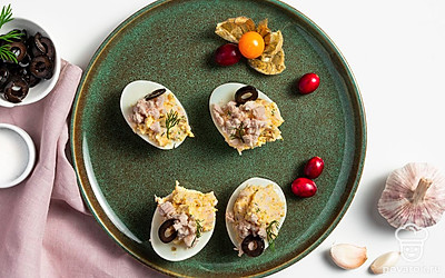 Яйца, фаршированные сыром и чесноком, украсьте кружочками маслин.