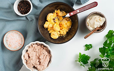 Приготовьте начинку. Листики петрушки отделите от стеблей и мелко нарежьте. Желтки тщательно разомните при помощи вилки. Добавьте печень трески, разомните ее вилкой и перемешайте, чтобы получилась однородная масса. Всыпьте зелень, перемешайте. Добавьте майонез. Посолите и поперчите по вкусу.