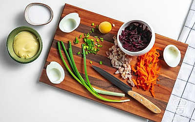 Подготовьте ингредиенты для начинки яиц. Яйца разрежьте пополам, желтки отделите, раскрошите. Свеклу и морковь натрите на средней терке. Зеленый лук нашинкуйте. Чеснок продавите через пресс. Селедку очистите, уберите косточки, разделайте на филе и мелко нарежьте. Лимон для подачи нарежьте на тонкие дольки.