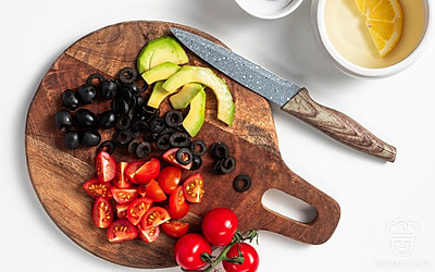 Подготовьте продукты. Соедините масло и лимонный сок для заправки. Если нужно, подсолите по вкусу. Помидоры черри разрежьте на 4 части. Маслины нарежьте колечками, авокадо — тонкими дольками.