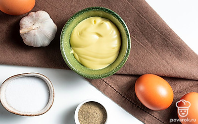 Яйца помойте, налейте в кастрюлю воды, положите в нее яйца и доведите до кипения. После этого варите яйца около 7 минут. Залейте их холодной водой после готовности, это поможет быстрее очистить яйца от скорлупы. Петрушку помойте и удалите грубые стебли. Чеснок очистите от шелухи и пропустите через пресс.