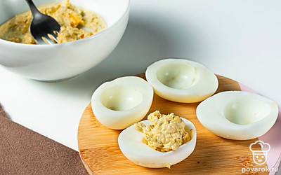 Сделайте начинку. Добавьте к желткам измельченный чеснок. В эту же емкость добавьте майонез. Посолите, поперчите ингредиенты по вкусу и перемешайте до однородной массы. Нафаршируйте начинкой каждый белок с помощью чайной ложки.