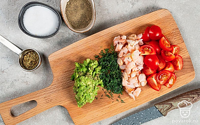 Подготовьте ингредиенты для блюда. Авокадо разделите пополам, аккуратно выньте косточку. С помощью ложки отделите мякоть авокадо. Разомните мякоть вилкой. Томаты черри мелко нарежьте. Креветки нарубите. Укроп накрошите.