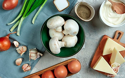 Очистите лук от шелухи и нарежьте мелкими кубиками. Шампиньоны оботрите влажным кухонным полотенцем или ополосните под проточной водой и насухо вытрите. Мелко нарежьте грибы, размер кусочков не должен превышать размер нарезанного лука. Сыр натрите на мелкой терке. Зеленый лук ополосните, обсушите и мелко порубите. Чеснок очистите и пропустите через пресс. Зелень для подачи вымойте, обсушите.