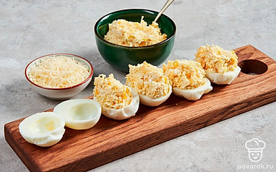 Сделайте начинку. Болгарский перец нарежьте максимально мелкими кубиками и отправьте к желткам. В эту же емкость поместите творог, добавьте майонез и перемешайте до однородной массы. По желанию можете слегка посолить. Нафашируйте белки начинкой и посыпьте тертым сыром.