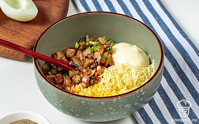 Закончите приготовление начинки. На терке натрите сыр и чеснок, переложите ингредиенты в отдельную емкость и перемешайте. Туда же добавьте 1 ст. л. майонеза, еще раз перемешайте. Куриные яйца разрежьте на две части, извлеките из них желтки и натрите их на терке. Затем добавьте желток к смеси сыра и чеснока. Туда же отправьте оставшийся майонез и обжаренные грибы. Все ингредиенты тщательно перемешайте.