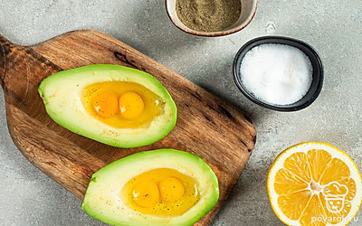 Подготовьте продукты. Сбрызните авокадо лимонным соком. В каждую половинку плода разбейте по два перепелиных яйца . Посолите их и поперчите.