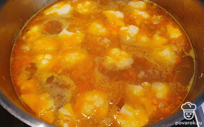 В бульон выложить лук с морковью, мелко нарезанный чеснок и цветную капусту, разобранную на соцветия. Варить до готовности. 