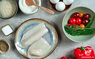 Тушку кальмара разморозьте, очистите от кожи и хребта. Рис промойте, отварите до полуготовности и промойте. Яйца замочите в 3%-ном растворе соды и промойте, затем сварите и очистите остывший продукт, оставив одно яйцо сырым. Укроп вымойте, обсушите и мелко порубите. Перец, свежий огурец, базилик и томаты черри вымойте и просушите. Перец очистите от плодоножки и семен, у огурца срежьте концы. Нарежьте перец и огурец ломтиками, базилик измельчите, черри оставьте целыми. Прогрейте духовку до 200 градусов и подготовьте форму для запекания блюда.
