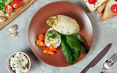 Тушку кальмара положите на тарелку, разрежьте ее на дольки, полейте соусом, в котором он запекался. Рядом выложите ломтики огурца и перца, целые томаты черри, сверху украсьте листьями базилика.