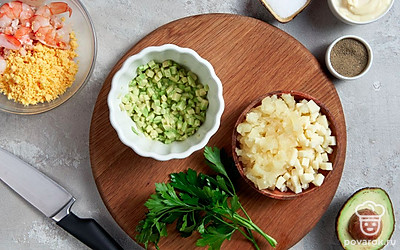 Сделайте начинку. Нарежьте ананас и сыр маленькими кубиками. Отложите 4 креветки для украшения, остальные нарежьте небольшими кусочками. Измельчите зелень. Яйца разрежьте пополам, извлеките желток и нарежьте его мелкими кусочками. В миску добавьте нарезанные ананасы, твердый сыр, авокадо, креветки, желтки и зелень, все хорошо перемешайте.