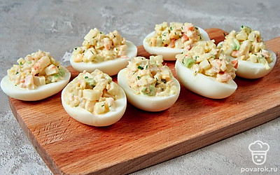 Зафаршируйте яйца. Посолите и поперчите начинку по вкусу, добавьте майонез. Приготовленной салатной смесью нафаршируйте половинки белков.