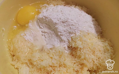 Переложите натертый сыр в удобную глубокую посуду, добавьте туда разбитое яйцо и просеянную муку. Все хорошо перемешайте до однородной массы.
