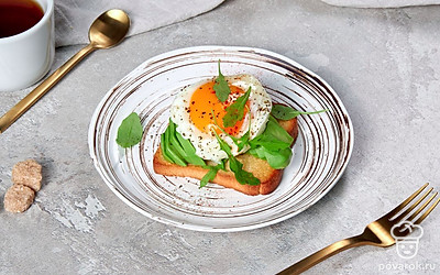 Перед подачей тост с авокадо и яйцом оформите свежей зеленью.