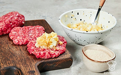 Сформируйте закуску. Для этого возьмите немного фарша и сформируйте из него приплюснутую котлету. Сверху выложите немного яичной начинки, накройте ее еще одной котлетой. Получившуюся закуску подравняйте, чтобы она стала более округлой. Повторите действия со всем фаршем.