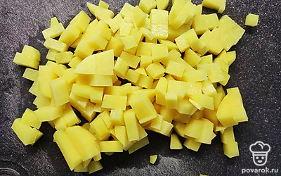 Картошку почистить и нарезать кубиком. Отправить в бульон. Поставить кастрюлю на огонь и подождать, когда вода закипит. Затем добавить зажарку.