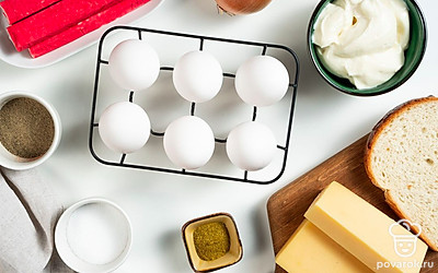 Подготовьте продукты для закуски. Крабовые палочки нарежьте кубиками. Лук почистите, измельчите. Хлебный мякиш замочите в теплой воде. Пармезан натрите на средней терке.