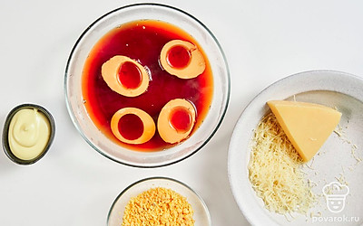 Подготовьте яйца. Выложите яйца в просторную емкость. Налейте холодную воду. Поставьте на средний огонь. Доведите до кипения. Варите до крутого состояния 10 минут. По окончании варки сразу переложите яйца в холодную воду. Затем аккуратно почистите и ополосните под краном. Острый кончик яйца срежьте. Ложкой переложите желток в миску для начинки. Срезанные части яйца замочите в заварке для окрашивания на 5 минут. Затем обсушите.