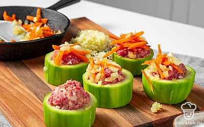 Нафаршируйте кабачки. Противень покройте фольгой и разложите на ней кружочки кабачков. В центр каждого кружка плотно выложите мясную массу. Сверху распределите морковь с луком и смажьте слой майонезом. Натрите сыр на средней терке и посыпьте им кабачки.