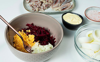 Приготовьте фаршированные яйца. В посуду положите тертую свеклу, посолите. Добавьте майонез, желток, измельченную селедку, чеснок. С лука слейте жидкость, выложите его к свекле. Тщательно перемешайте. В белки яиц положите начинку. Сверху выложите ломтики селедки.