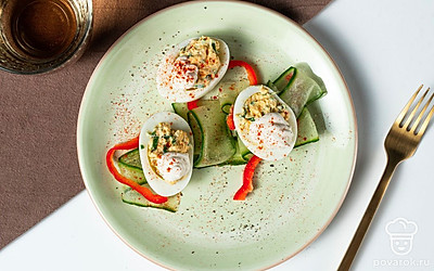 На сервировочном блюде разложите кольца сладкого перца, внутрь выложите тонкие круглые ломтики огурцов. Сверху на огурцах разместите фаршированные яйца с майонезом.