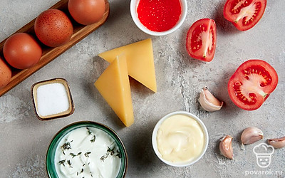 Чеснок очистите от шелухи и выдавите через пресс. Помойте яйца. Помойте и мелко нарежьте помидор. Сыр натрите на мелкой терке. Смешайте майонез со сметаной.