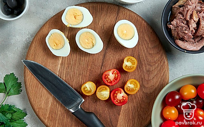 Подготовьте яйца и начинку. Яйца разделите пополам, выньте желток и разомните его. Петрушку мелко порубите ножом. В миску с печенью трески добавьте желток, петрушку, майонез и молотый перец.