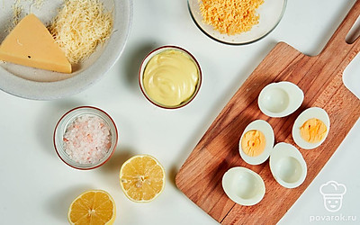 Займитесь яйцами. Отварите яйца вкрутую в течение 8-10 минут. Остудите, очистите от скорлупы. Смочите лезвие ножа в воде. Разделите яйца вдоль на две равные части. Желток уберите в отдельную посуду.