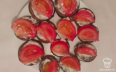 Кружочки баклажана смажьте майонезом с чесноком и зеленью. Сверху выложите ломтики помидора, а затем посыпьте тертым сыром.