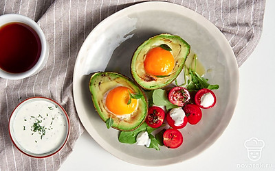 Половинки авокадо выложите на тарелку овальной формы, посыпьте петрушкой, рядом выложите половинки помидоров черри.