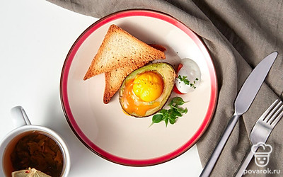 Готовую закуску из авокадо и куриных яиц подавайте к столу в горячем виде. В качестве украшения используйте зелень. Отделите листья от веточек и выложите их поверх блюда.