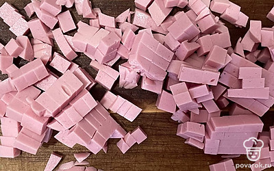 Колбасу нарежьте кубиком и переложите в кастрюлю.