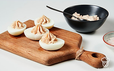 Приготовьте фаршированные яйца с треской. Для начинки смешайте желтки, майонез, печень трески, репчатый лук. Добавьте соль и перец по вкусу, перемешайте. Нафаршируйте яичные белки рыбной начинкой.