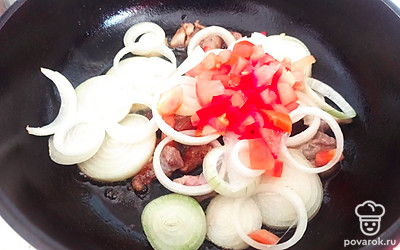 Лук нашинкуйте кольцами. Выложите вместе с помидором к мясу. Обжаривайте на медленном огне 3-5 минут. 